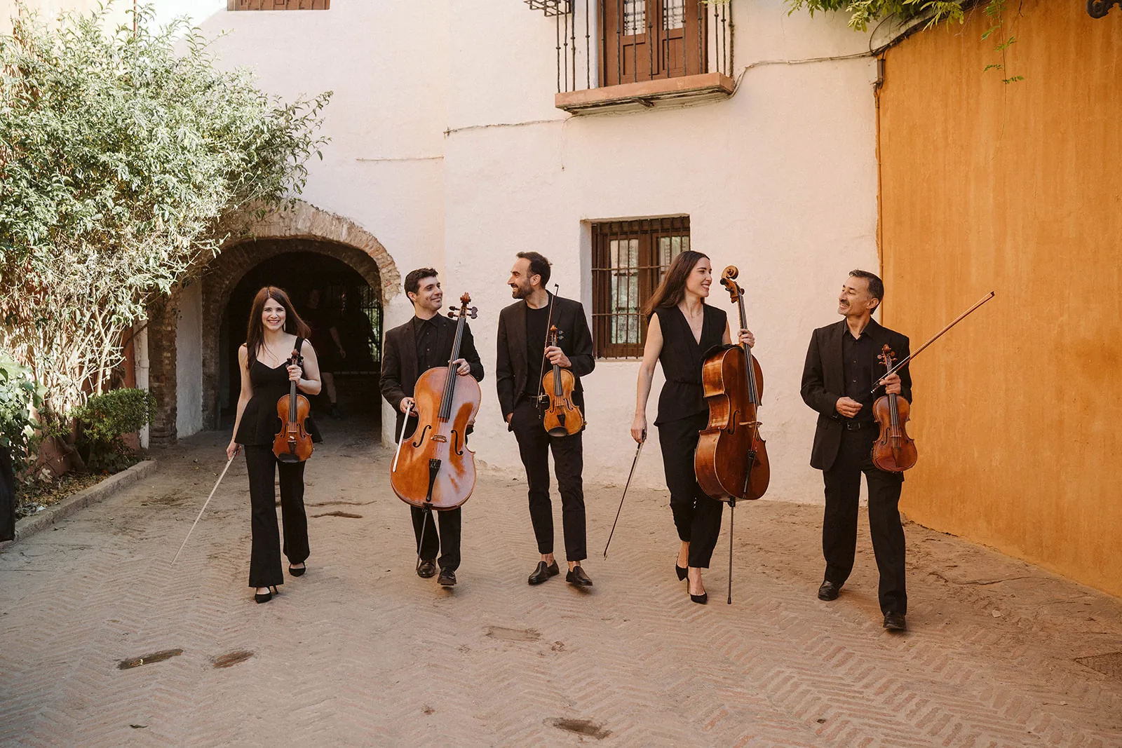 A string quintet of Música Para Boda walking through a courtyard in Seville